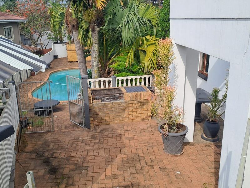 Outdoor entertainment area featuring a swimming pool, paved patio, and a built-in brick braai facility, ideal for relaxed outdoor living.