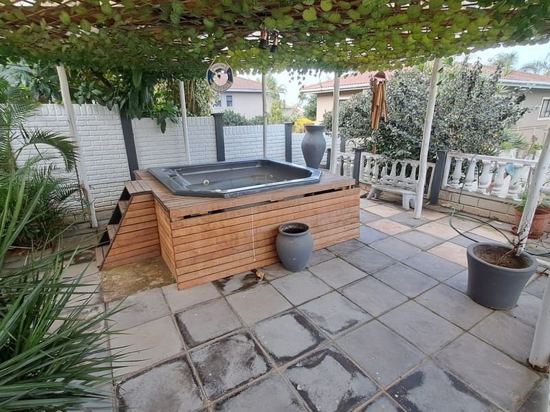 Outdoor patio area featuring a built-in jacuzzi, tiled flooring, and a covered pergola structure, providing a private space for relaxation.
