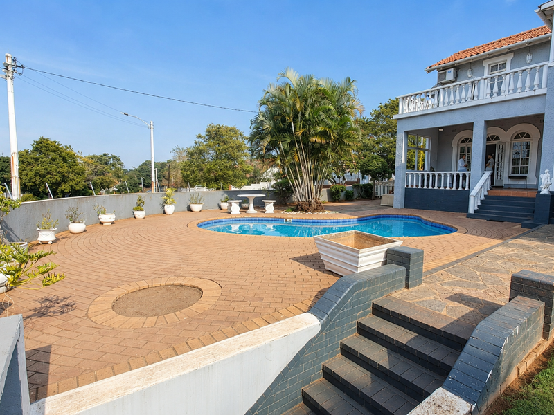 Spacious outdoor pool area featuring a paved patio, tiered staircase, and a balcony overlooking the swimming pool.