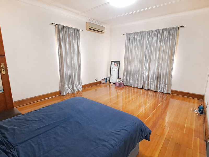 Spacious bedroom featuring polished hardwood flooring, a wall-mounted split-system air conditioner, and classic timber door finishes.
