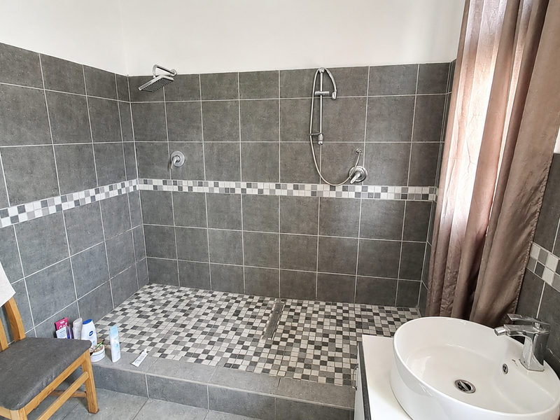 A modern bathroom featuring a spacious walk-in shower with dual shower heads, mosaic tile accents, and a contemporary vessel sink vanity.