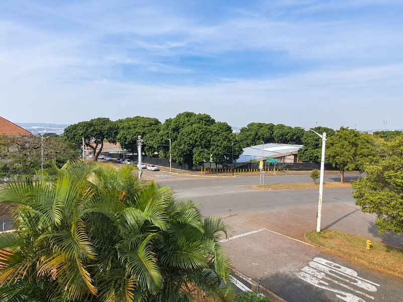 An elevated view overlooking a suburban street intersection with mature trees and surrounding residential infrastructure.