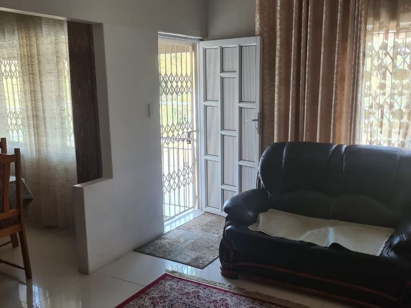 A living room area featuring tiled flooring, decorative ceiling cornicing, and a secure entrance door with an integrated security gate.