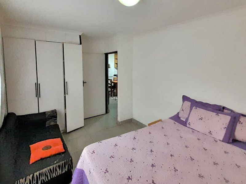 A functional bedroom featuring built-in cupboards, tiled flooring, and neutral wall finishes, providing a practical living space.