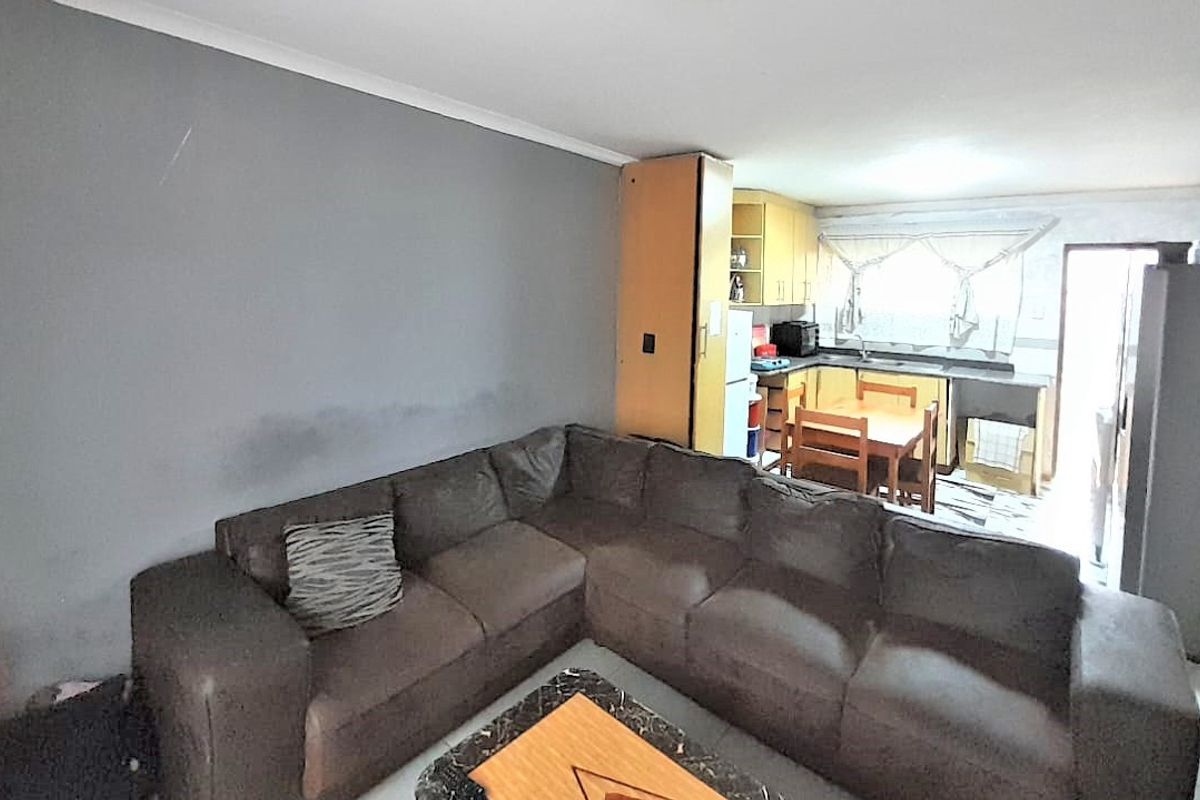 Open plan living and kitchen area featuring built-in cabinetry and sink, requiring cosmetic updates to the wall finishes.