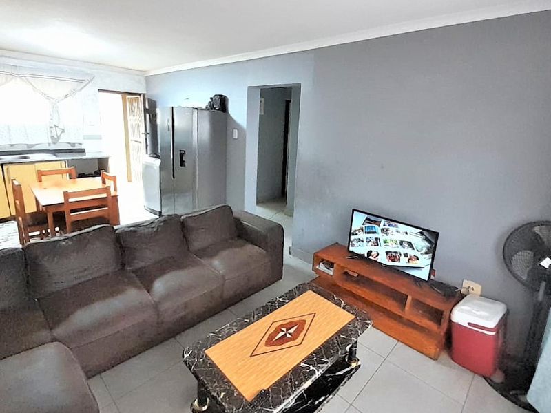 Open plan living area featuring tiled floors and a connected kitchen space with built-in cabinetry and countertops.