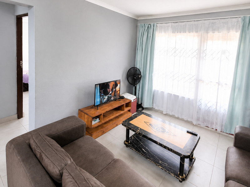A living room featuring tiled flooring, a sliding glass door with security gate, and neutral wall finishes.