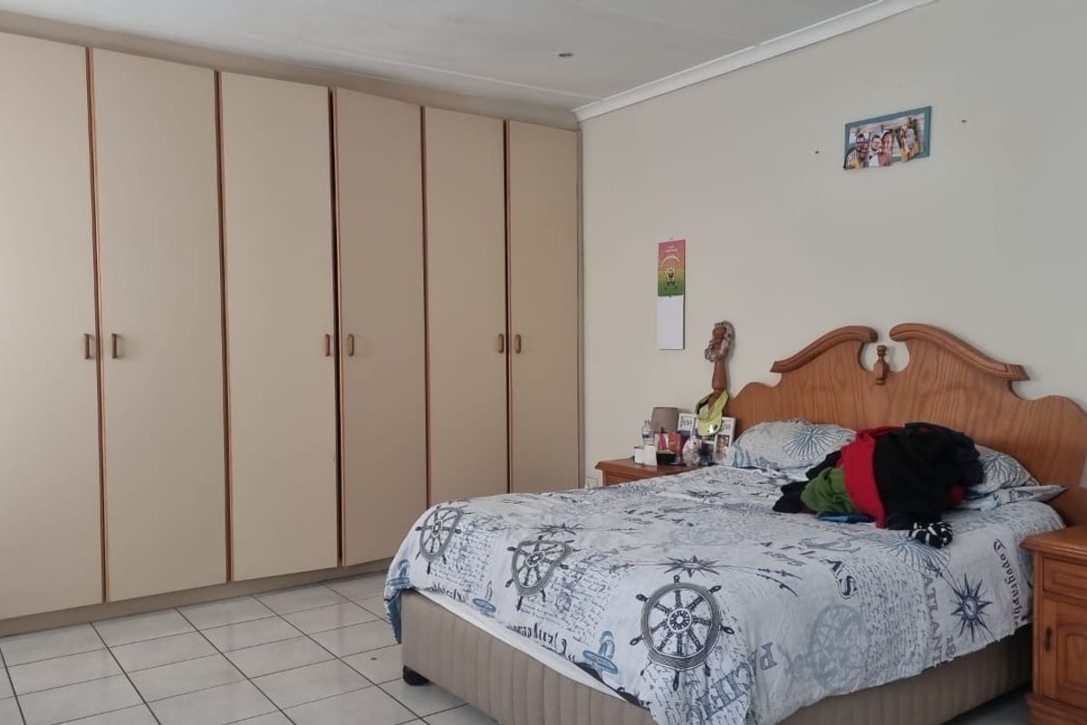 Spacious bedroom featuring extensive built-in cupboards and neutral tiled flooring, offering ample storage and a functional layout.