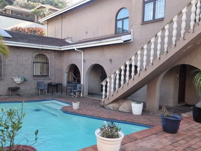 Outdoor pool area featuring brick paving, an external staircase with balustrades, and arched architectural details on the building facade.