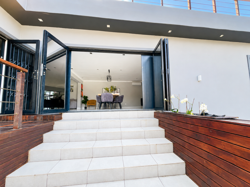 A modern outdoor patio featuring tiled steps, timber decking, and large bi-fold doors providing seamless access to the interior living space.