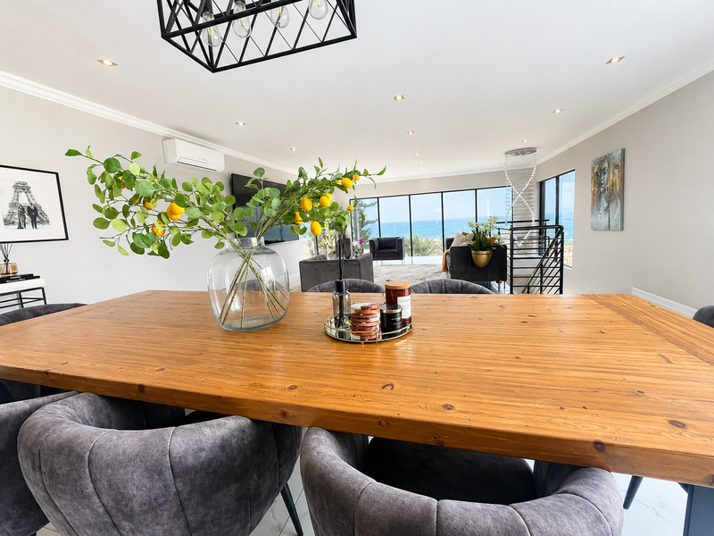 Spacious open-plan living and dining area featuring modern tiled floors, recessed lighting, and expansive floor-to-ceiling windows with panoramic ocean views.