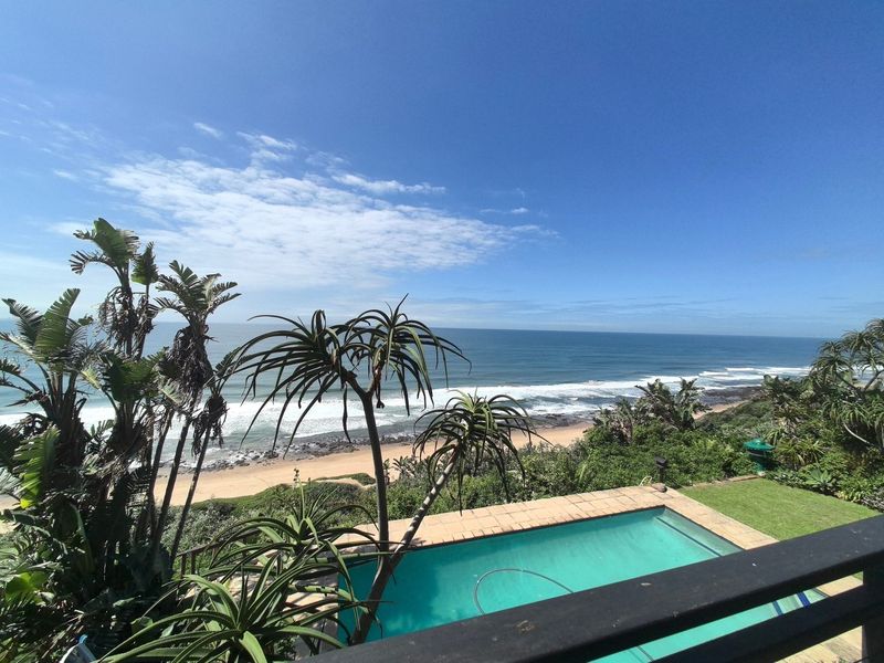 Elevated view overlooking a private swimming pool with a scenic ocean and beach backdrop.
