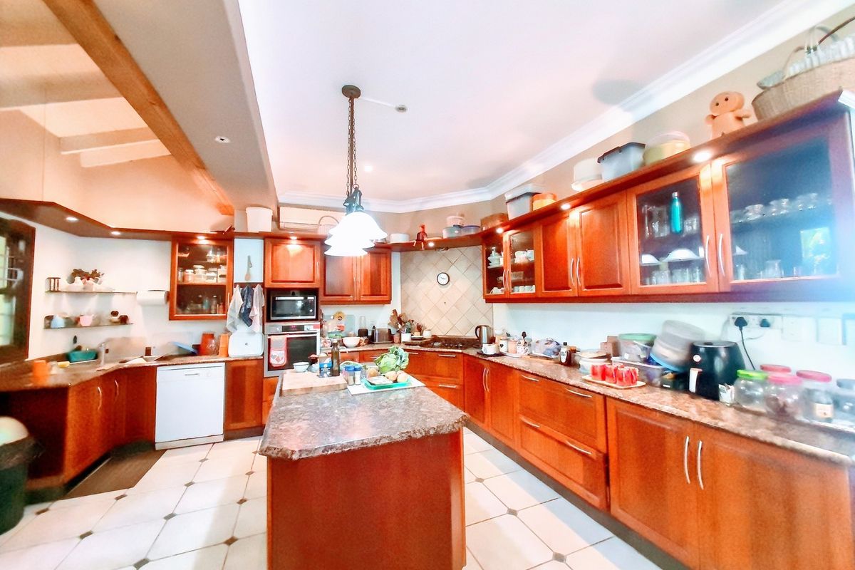 Spacious kitchen featuring extensive wooden cabinetry, granite countertops, a central island, and tiled flooring, offering ample storage and workspace.