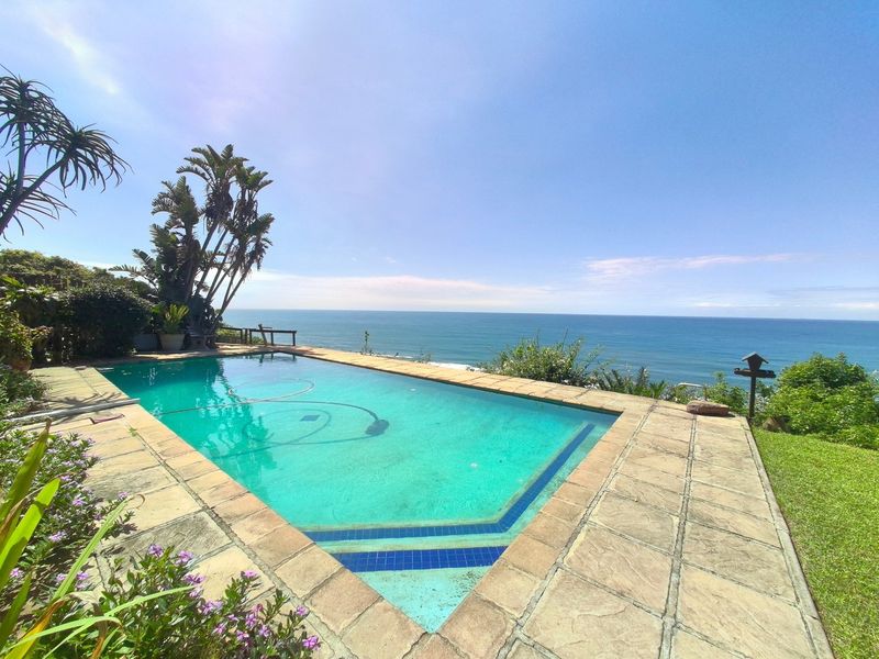 Outdoor swimming pool area featuring stone paving and expansive ocean views, providing a serene coastal setting.