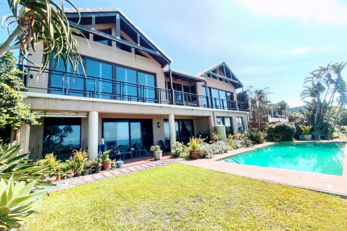 Rear elevation of a double-story residence featuring a swimming pool, paved patio area, and upper-level balcony with sliding glass doors.