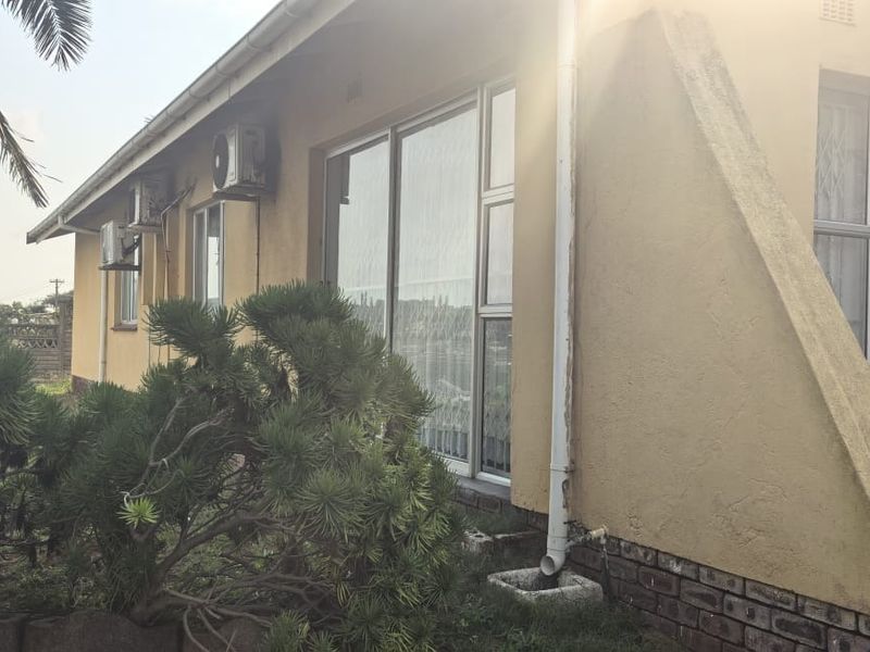 Rear exterior view of the house featuring sliding glass doors, aluminium window frames, and wall-mounted air conditioning units.