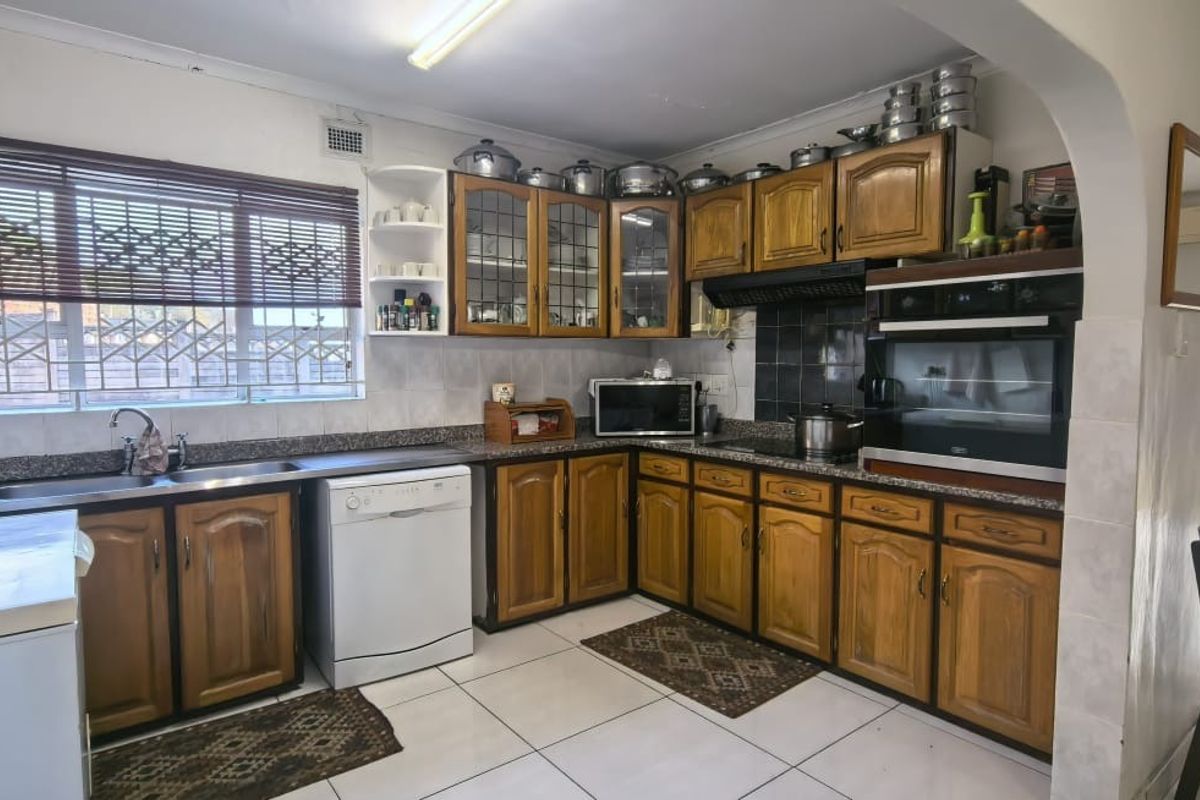 A functional kitchen featuring wooden cabinetry, granite countertops, built-in oven, and tiled flooring, offering a classic layout with potential for modern updates.
