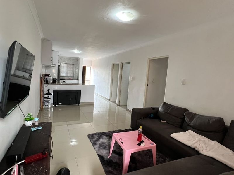 Open-plan living area featuring tiled flooring and a connected kitchen space, providing a functional layout for modern apartment living.