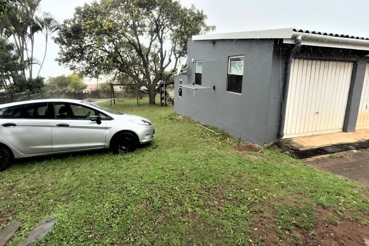 Rear view of the property showing a double garage with painted exterior walls and surrounding lawn area.