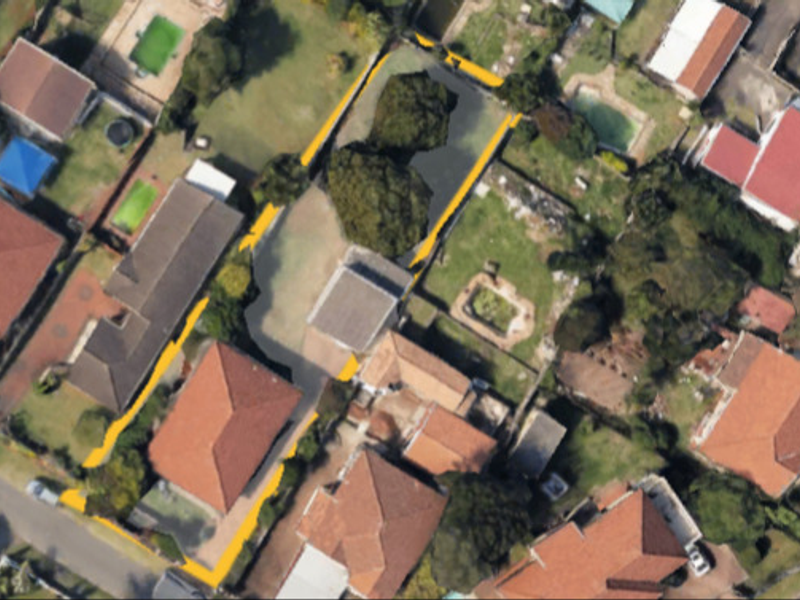 An aerial view of the property showing the building footprint, roof structure, and surrounding garden area within the plot boundaries.
