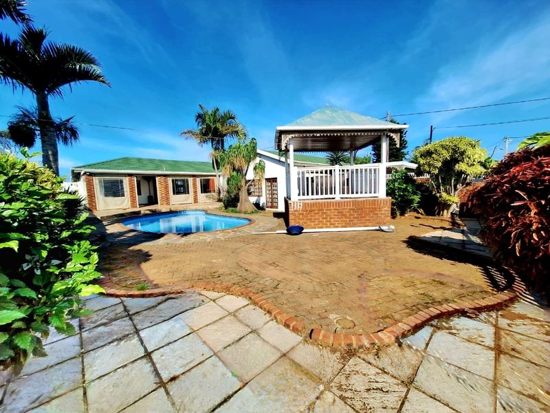 Outdoor entertainment area featuring a swimming pool, brick paved patio, and a covered gazebo structure in a landscaped garden setting.