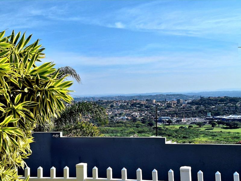 An elevated view overlooking the surrounding neighbourhood and landscape, framed by a modern boundary wall and picket fence.