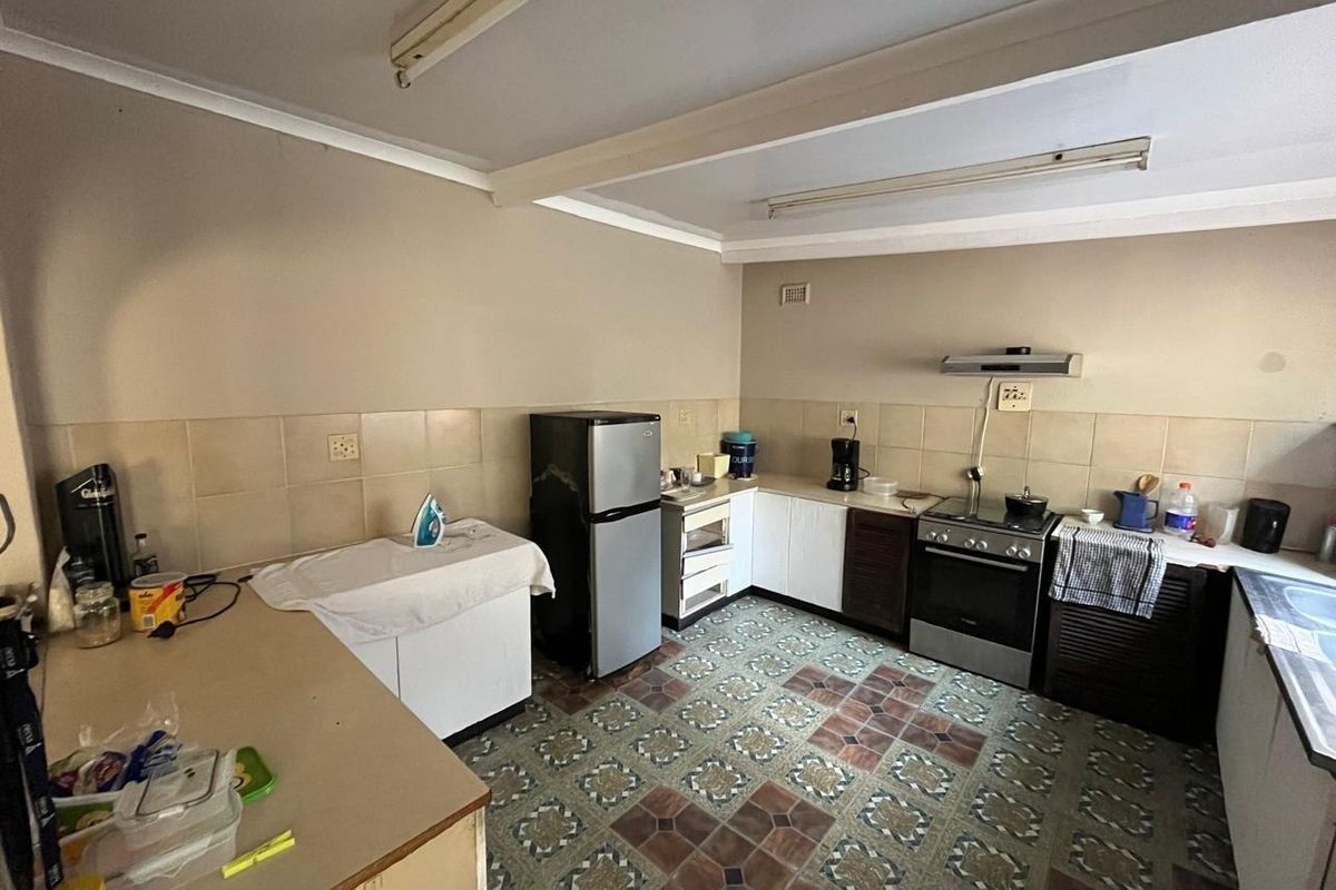 A functional kitchen featuring tiled flooring, built-in cabinetry, a tiled backsplash, and a freestanding oven with an extractor fan.