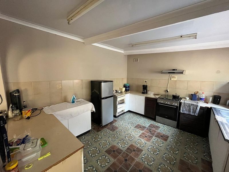 A functional kitchen featuring tiled flooring, built-in cabinetry, a tiled backsplash, and a freestanding oven with an extractor fan.