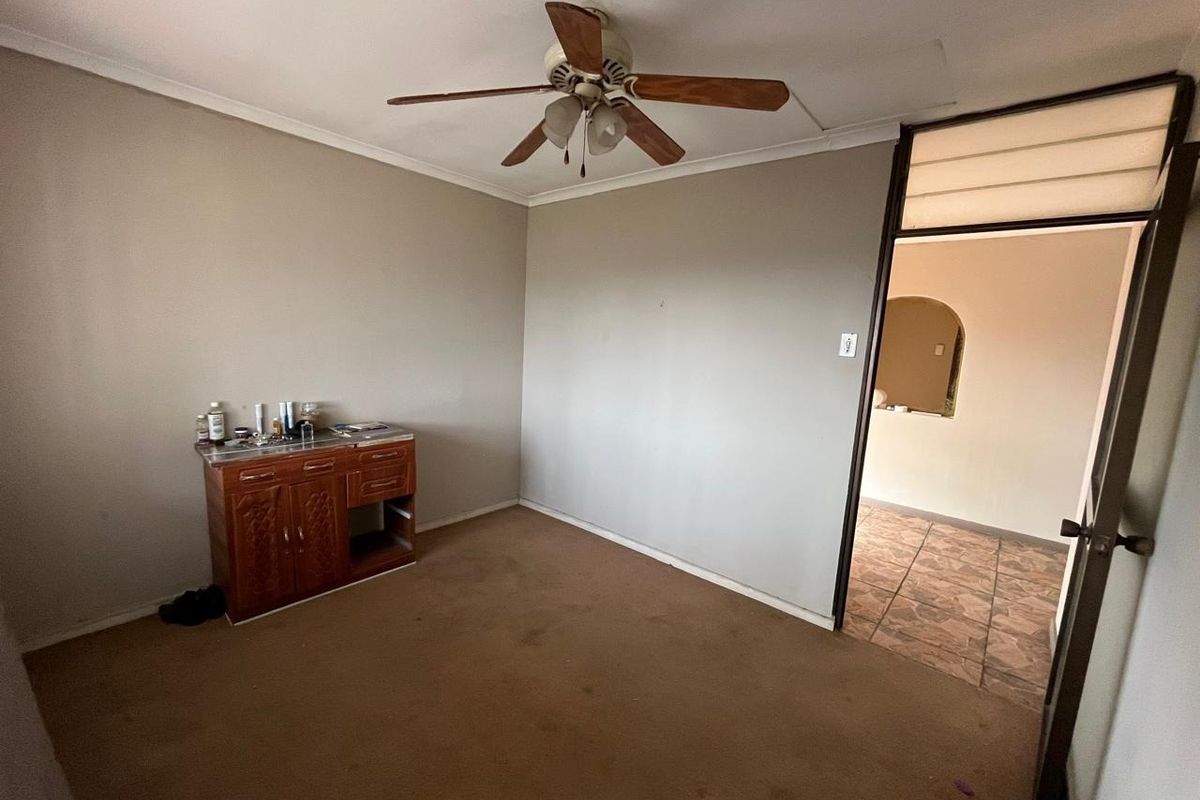 A vacant bedroom featuring a ceiling fan and carpeted flooring, requiring cosmetic updates to improve its overall condition and appeal.