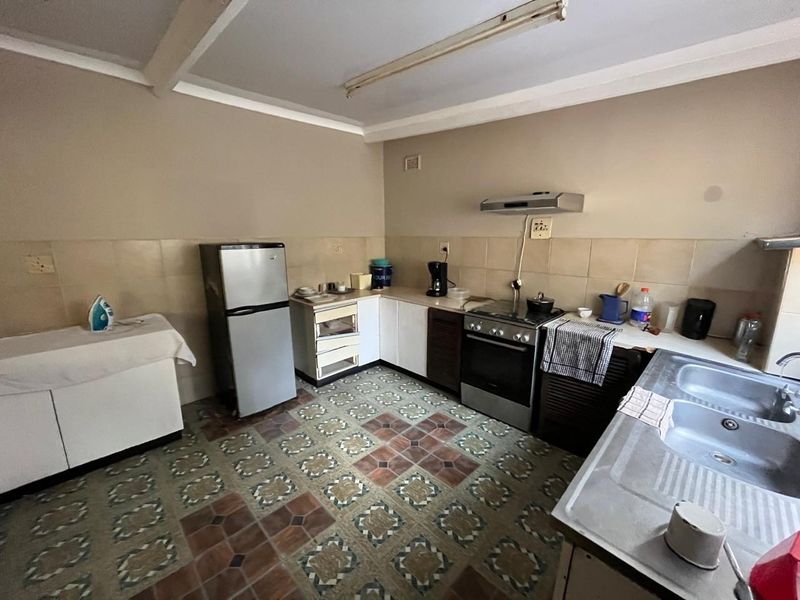 A functional kitchen featuring built-in cabinetry, a stainless steel double sink, and a freestanding stove with an extractor fan.