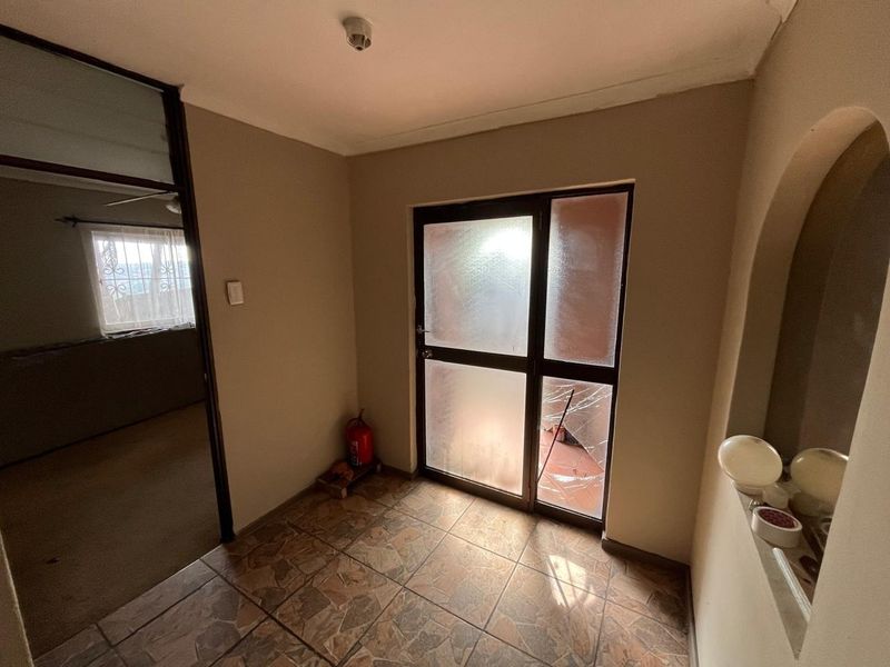 An entry foyer featuring tiled flooring, an arched wall detail, and a glass door with a visible crack in the lower panel.