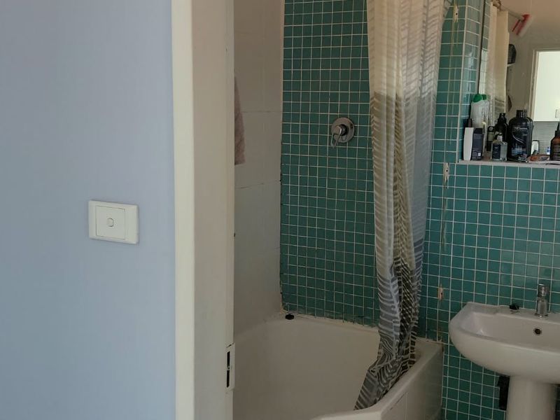 A dated bathroom featuring a pedestal sink, bathtub with shower mixer, and teal mosaic wall tiling.