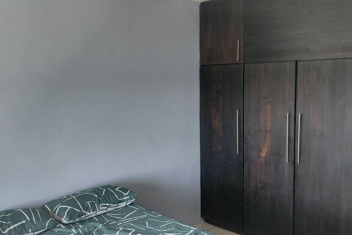 A bedroom featuring dark wood built-in cupboards providing ample storage space.