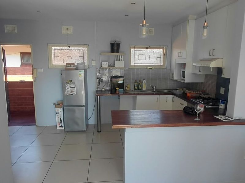 Functional kitchen featuring built-in cabinetry, a breakfast bar, gas hob, and tiled flooring, offering a practical layout for daily cooking and dining.