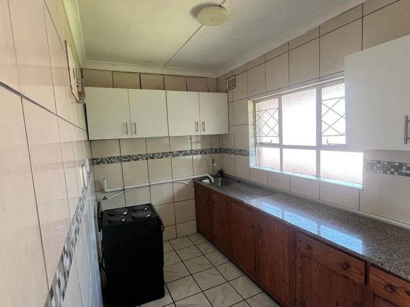 A functional kitchen featuring granite countertops, built-in cabinetry, and tiled finishes, offering a blank canvas for potential modern updates and renovation.