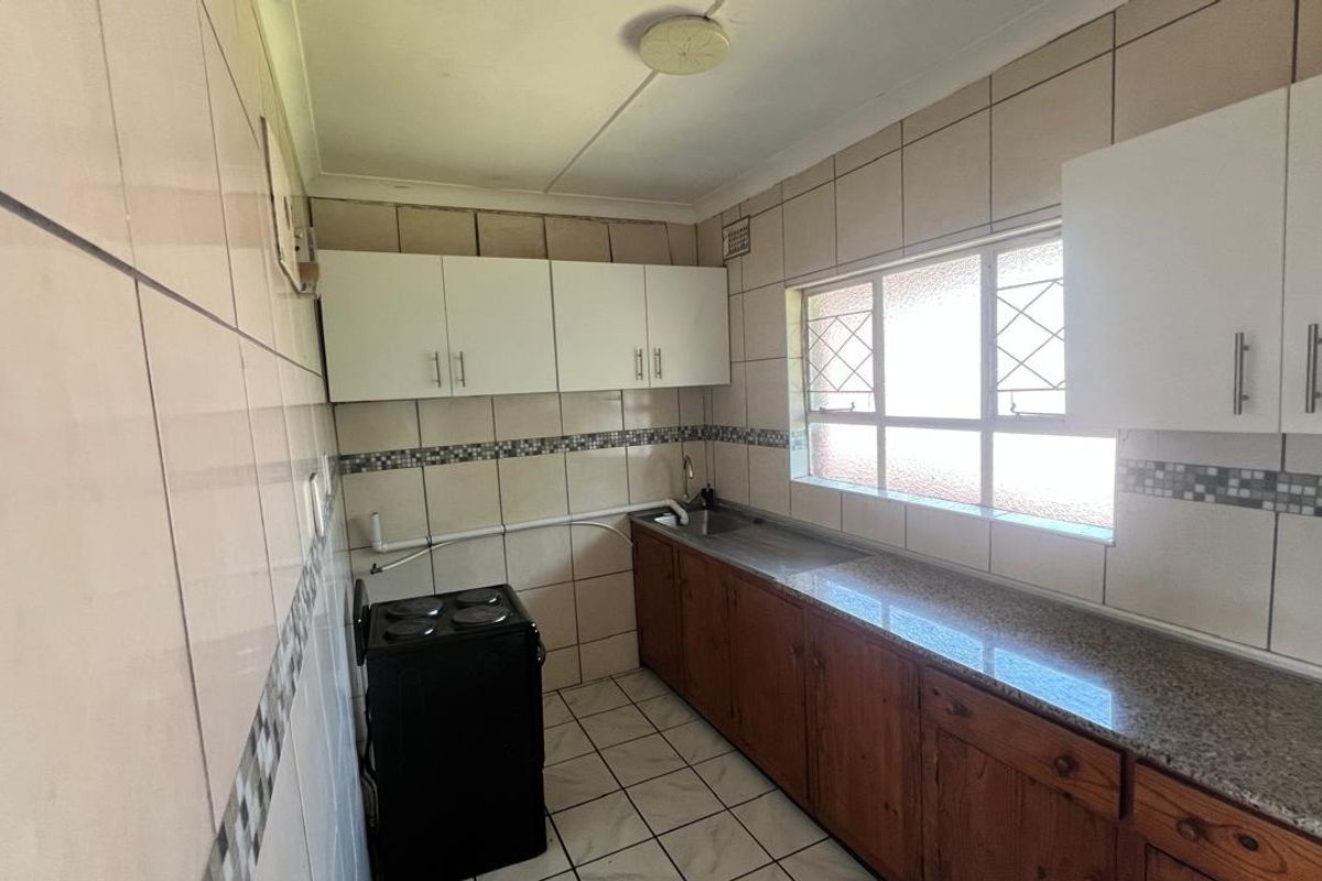 A functional kitchen featuring granite countertops, built-in cabinetry, and tiled finishes, offering a blank canvas for potential modern updates and renovation.