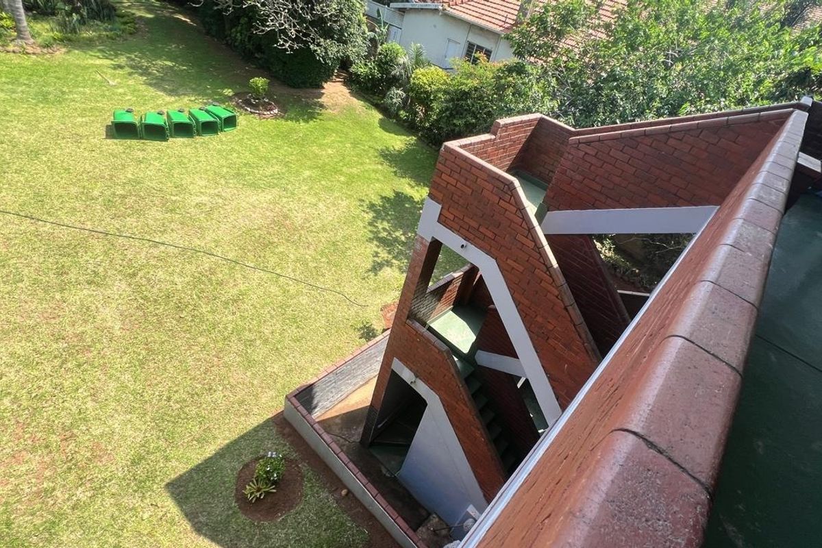An elevated aerial view showing the exterior brick staircase structure and the surrounding communal garden area of the apartment complex.