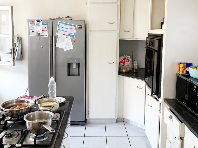 A functional kitchen featuring built-in cabinetry, a gas hob, and a built-in oven with tiled flooring and granite countertops.