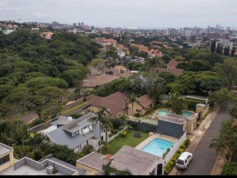 Aerial view of the residential property featuring a swimming pool, landscaped garden, and tiled roof, situated within a suburban neighborhood.
