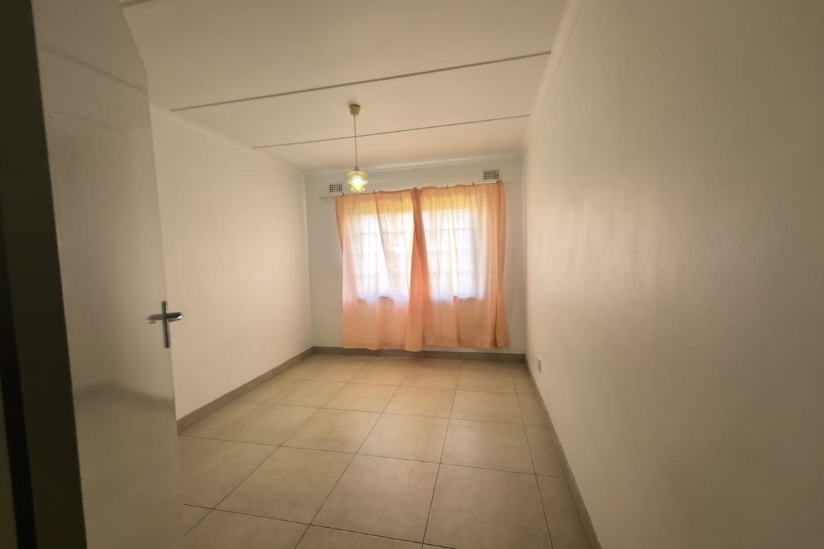 A clean, empty bedroom featuring neutral tiled flooring and a simple ceiling finish, ready for personalization.