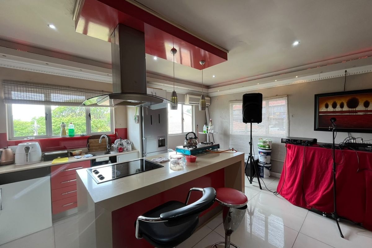 A kitchen featuring a central island with a built-in hob, extractor fan, and tiled flooring, offering a functional layout with integrated cabinetry.