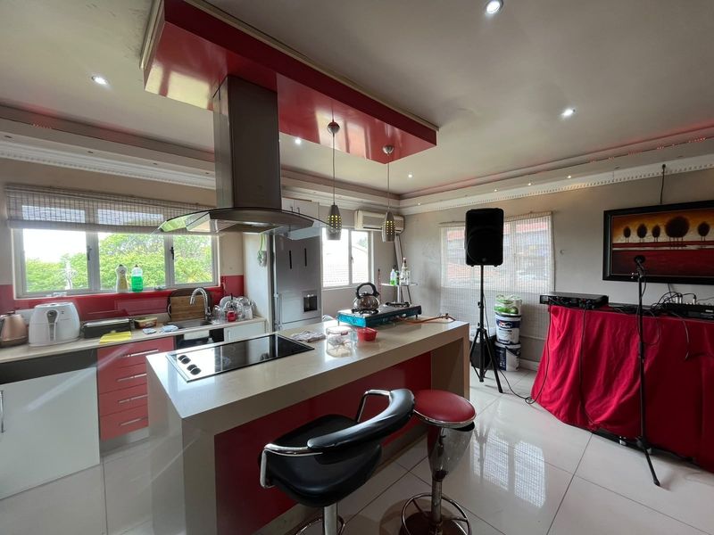 A kitchen featuring a central island with a built-in hob, extractor fan, and tiled flooring, offering a functional layout with integrated cabinetry.