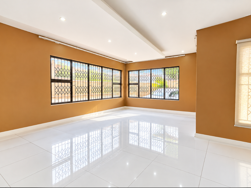 A bright, spacious, and empty living area featuring polished white porcelain floor tiles, recessed ceiling lighting, and large windows with integrated security gates.