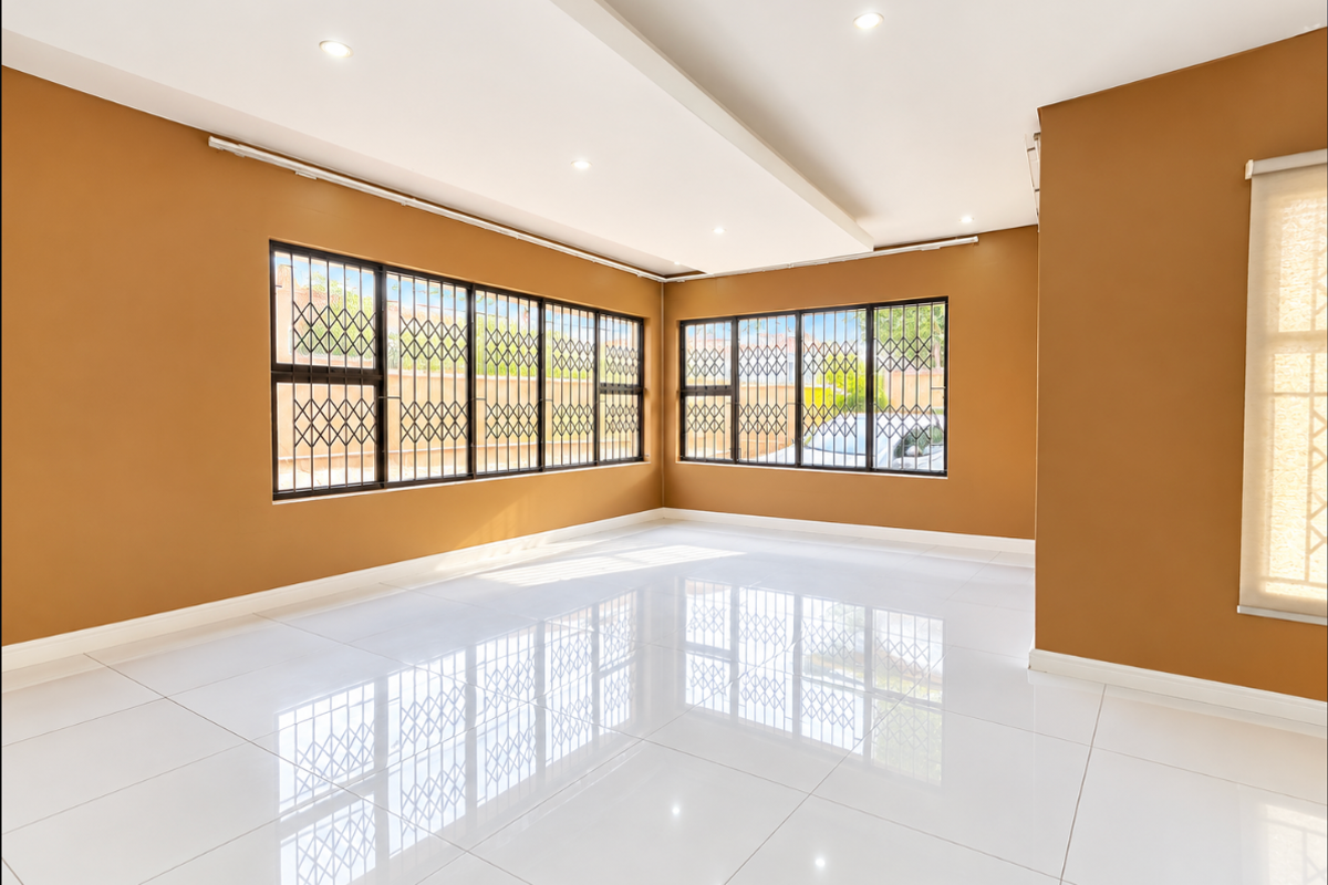 A bright, spacious, and empty living area featuring polished white porcelain floor tiles, recessed ceiling lighting, and large windows with integrated security gates.
