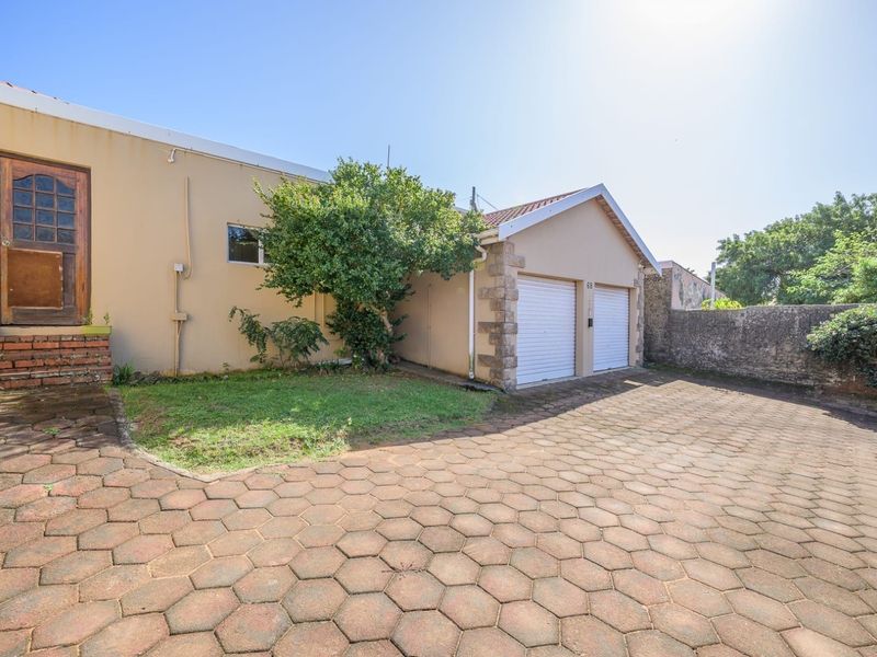 Front exterior view of the property featuring a double garage, paved driveway, and stone-clad accents.