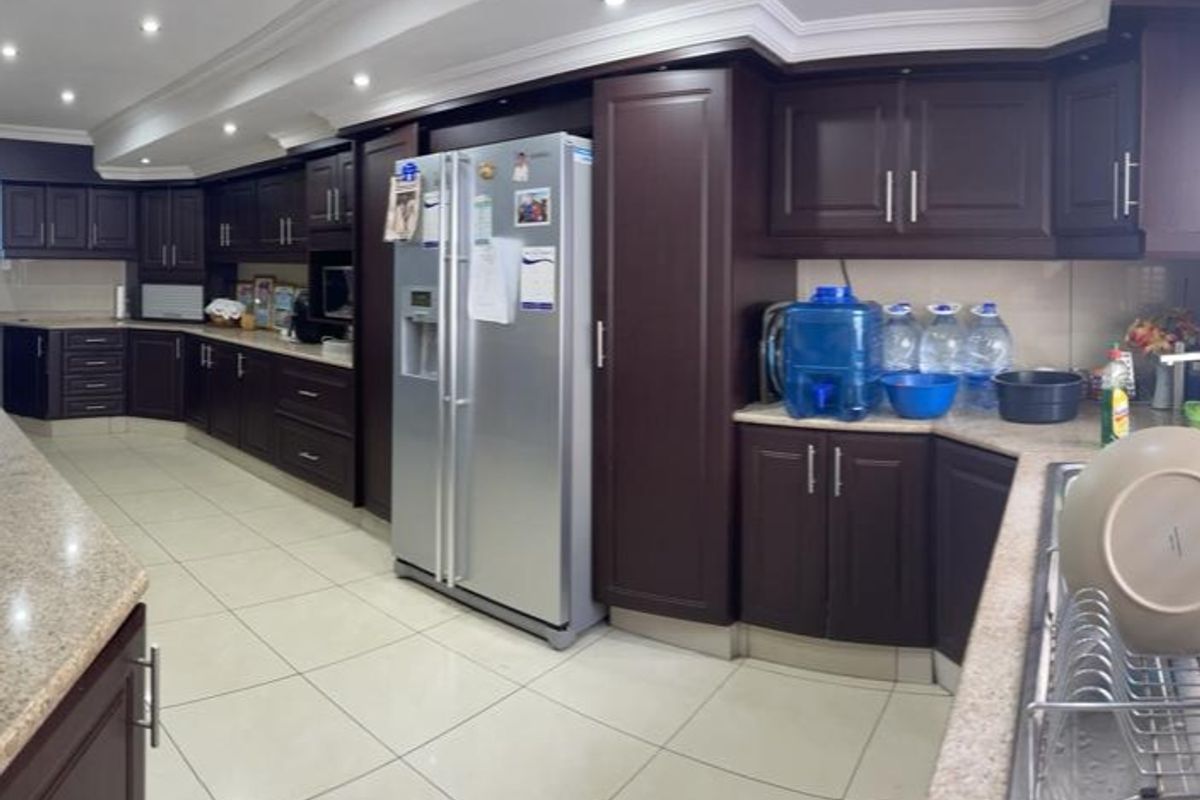 Spacious kitchen featuring dark wood cabinetry, granite countertops, recessed lighting, and tiled flooring, offering ample storage and workspace.