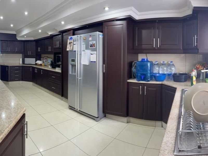 Spacious kitchen featuring dark wood cabinetry, granite countertops, recessed lighting, and tiled flooring, offering ample storage and workspace.