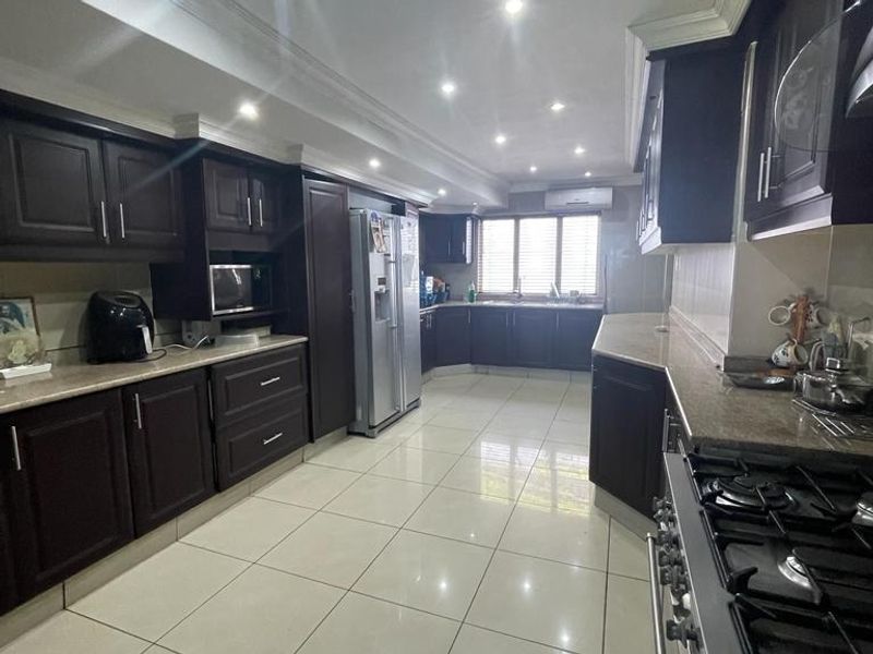 Spacious kitchen featuring dark wood cabinetry, granite countertops, gas hob, built-in oven, and tiled flooring with recessed lighting.