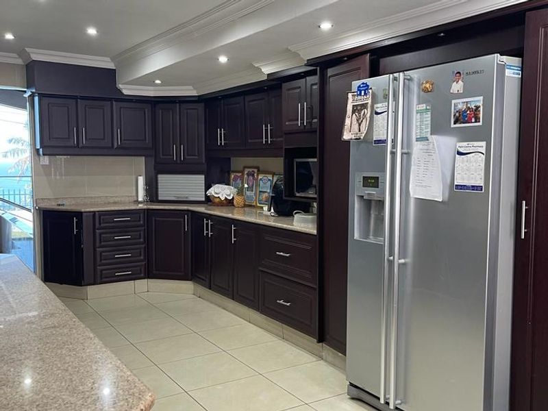 A well-maintained kitchen featuring dark wood cabinetry, granite countertops, tiled flooring, and recessed lighting, offering a classic and functional culinary space.