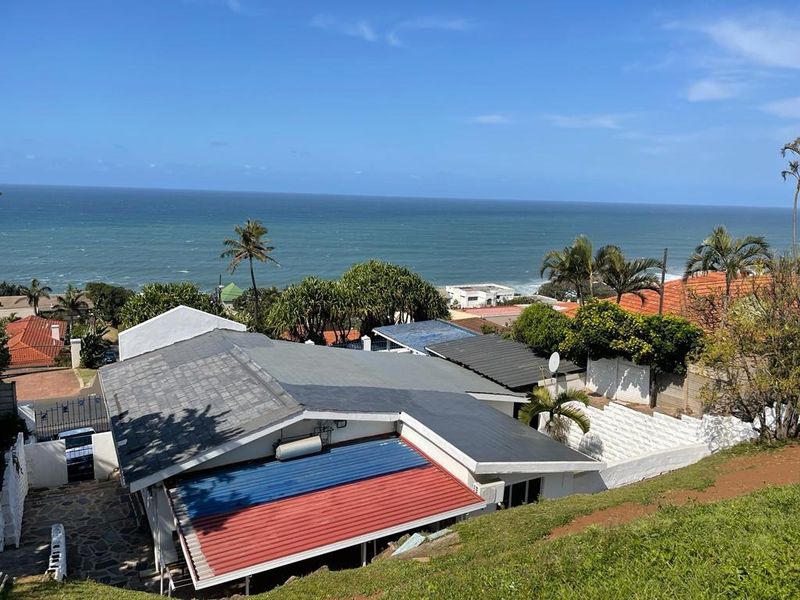 Elevated coastal view overlooking the property roofline, surrounding neighborhood, and the ocean horizon.